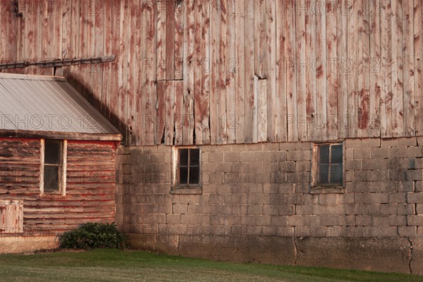 A rustic barn wall with wooden planks and brick foundation in rural setting in Ontario, Canada,