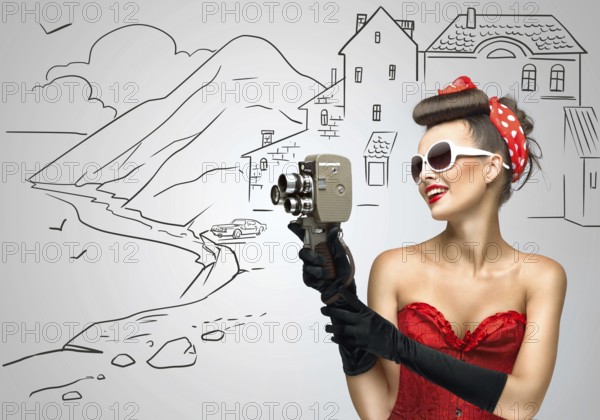 Glamorous pin up tourist girl filming a landscape with an old retro cinema 8mm camera, standing in