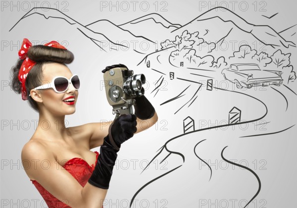 Glamorous pin up girl filming nature and landscape with an old retro cinema 8 mm camera, standing