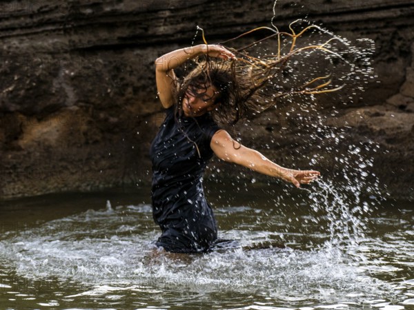 Middle-aged woman dancing and throwing water in the air, Maioris beach, llucmajor, Majorca,