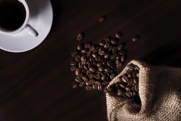 Coffee still life with cup, coffee beans in bag. Low key light