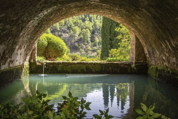 Tranquil, arched tunnel with views of water and trees in the background, Jardines de Alfabia
