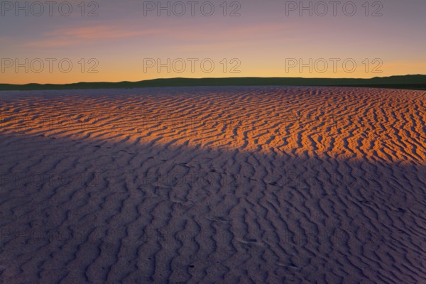 Orange sunset in the desert. Mesquite Flat Sand Dunes, California. The gentle slopes of the sand