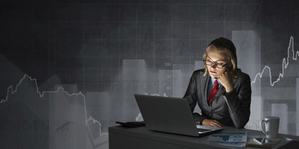 Attractive young businesswoman in glasses sitting at office desk and working at laptop. Female