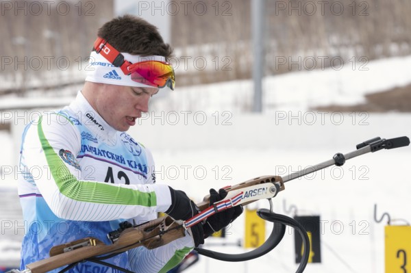 Biathlete reloads rifle before rifle shooting on shooting range. Sportsman biathlete Zlobin