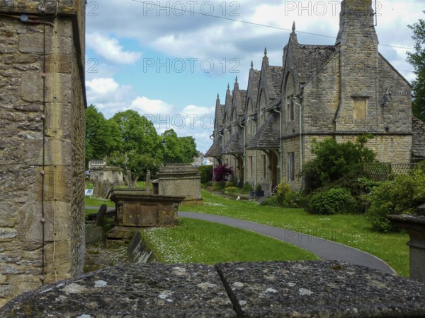 Charming cotswold stone houses stand alongside a serene cemetery, showcasing the timeless beauty of