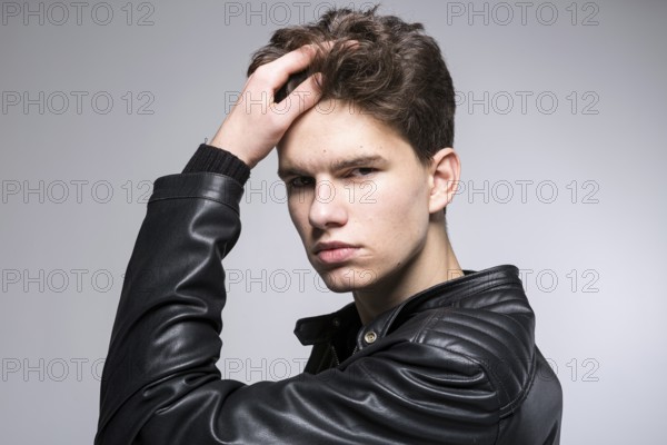Young fashion man passing his hand through his hair. Male fashion model with hand in hair. Man Hair