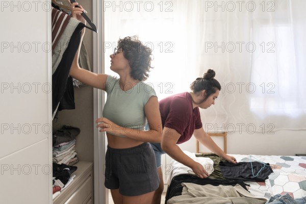 A joyful couple shares a playful moment together in a cozy bedroom, with sunlight filtering through