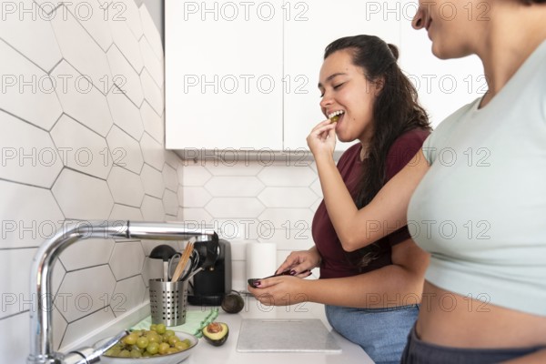 A cheerful lesbian couple shares a coffee break in their stylish kitchen. They enjoy a moment of