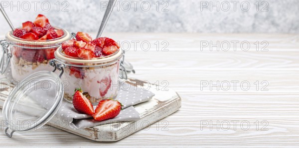 Parfait with Fresh Strawberries, Yoghurt and Crunchy Granola in Transparent Glass Mason Jars on