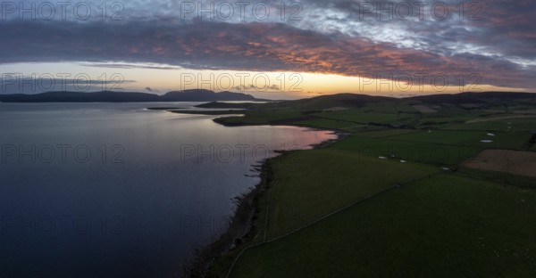 Sunset with cloud band on the coast of Scapa Flow with view to the island of Hoy, drone shot,