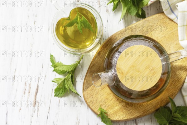 Cup and teapot of fresh natural herbal tea with fresh mint leaves on rustic wooden table. Organic