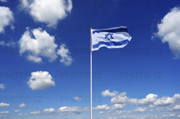 Flag of Israel fluttering in the blue sky with cumulus clouds