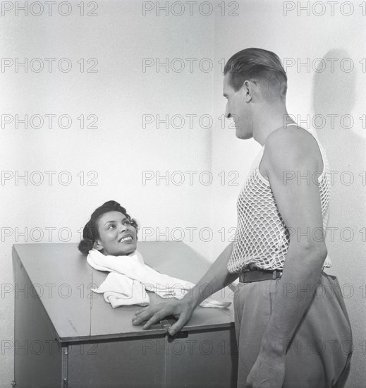 Beauty care in the 1950s. A young woman is sitting in a steam sauna, with only her head sticking up