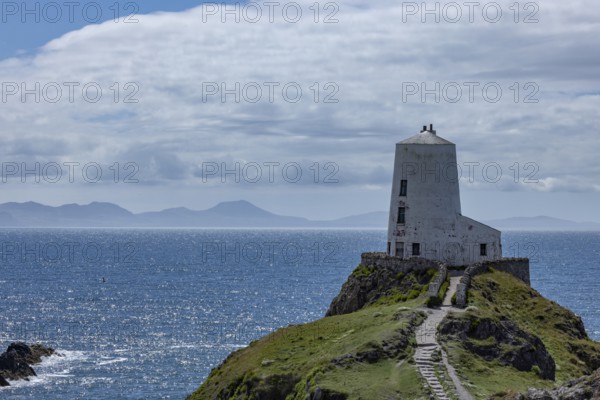 Twr Mawr Lighthouse, white lighthouse on a hill by the sea with blue sky and clouds, Ynys