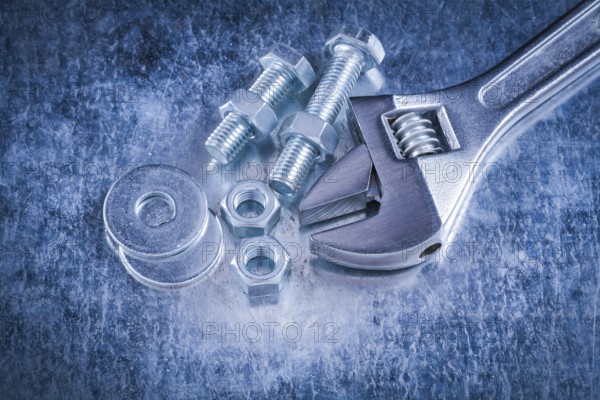 Metal adjustable wrench bolt washers screw-nuts and screwbolts on scratched metallic background