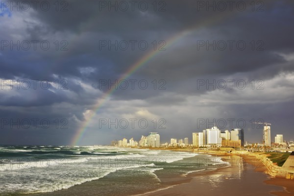 Storm cloud hanging over the sea, gorgeous huge rainbow crossed the sky. Promenade and beach in Tel
