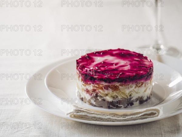 Layered salad herring under fur coat on table. Portion of traditional russian salad with herring,