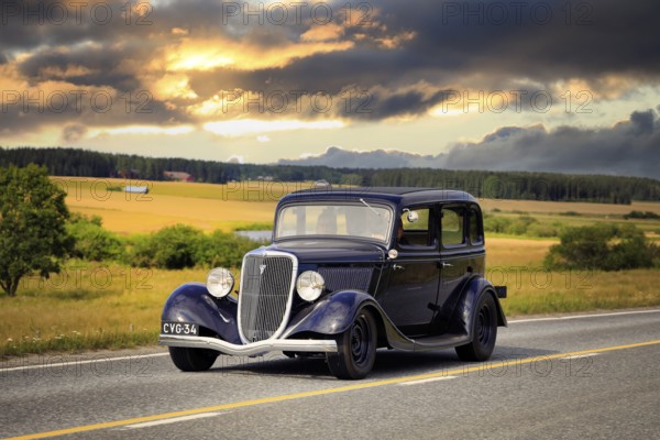 Black Ford Fordor Dillinger Special year 1934 on road on Maisemaruise 2019 car cruise. Edited sky.