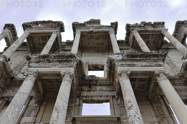 Ruins of an ancient library with impressive marble columns and detailed decorations under a blue