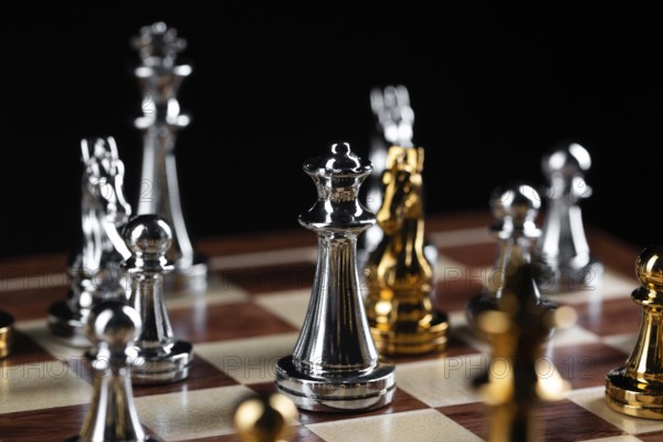 Gold and silver chess figures placed on wooden chessboard. Intellectual duel and tactical battle in