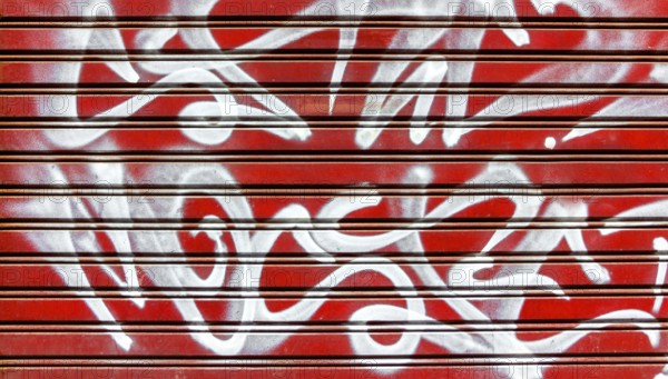 Red garage gate with vandalism sign of graffiti white spray paint. Ideal for concepts and
