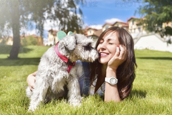 Pretty adult caucasian happy woman resting in the park on a sunny day with her beloved dog. Female