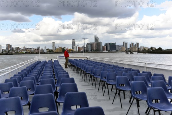 River cruise with empty chairs on the deck, modern city view in the background, London, London
