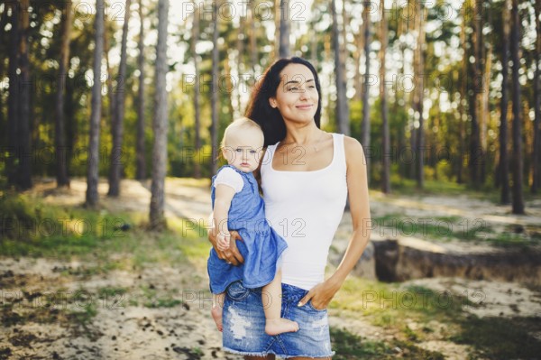 Young beautiful fashionable mother with long brunette hair holding a daughter's blonde with blue