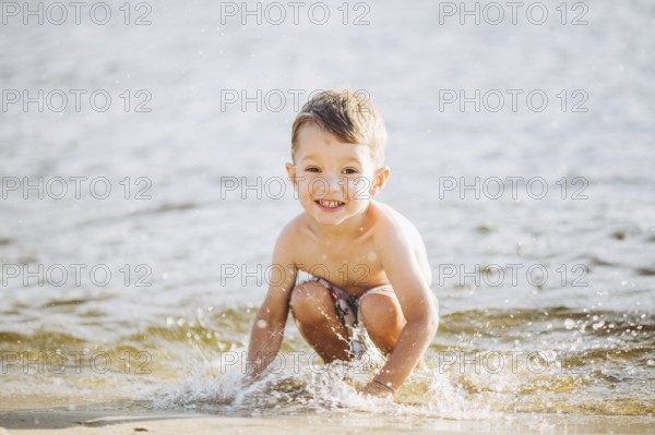 Theme is summer time and rest near the water. Little joyful Caucasian funny boy plays and enjoys in