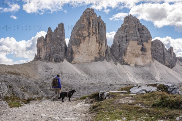 A female person hiking lonely with her dog around the Drei Zinnen mountains, the Dolomites in South