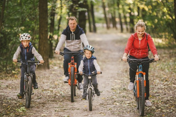 Parents and kids cycling on forest trail. family in warm clothes cycling autumn park. Family
