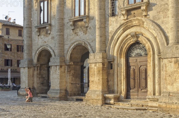 A tourist takes a photo into the sun on the Town Square Piazza Grande of Montepulciano, Tuscany,