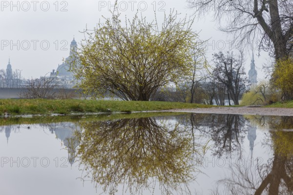 The towers of Dresden's old town are reflected in a puddle on the Königsufer when it rains,