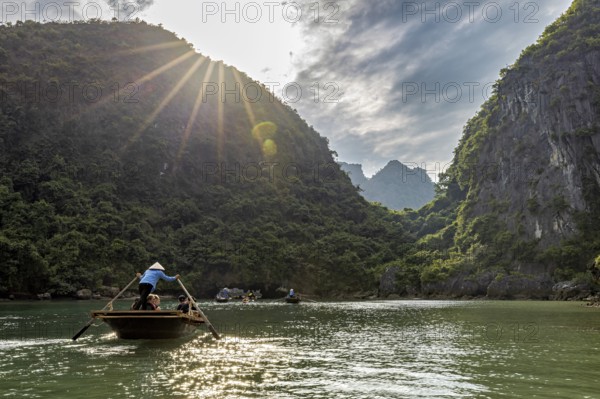 Boats in the river under bright sunlight and green mountains, rowing boats for tourists in Halong