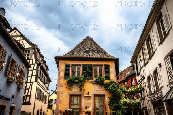 Characteristic half-timbered house with colourful shutters and floral decorations under a cloudy