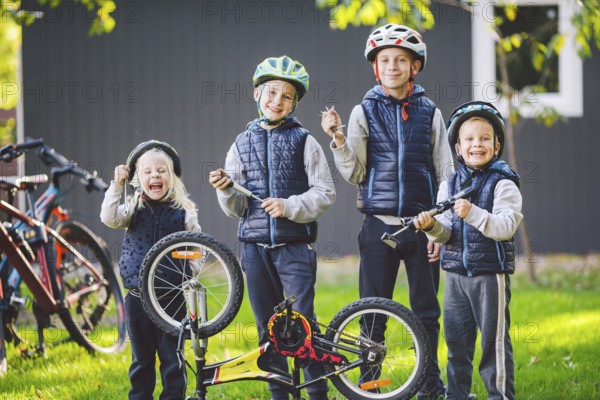 Children mechanics, bicycle repair. Happy kids fixing bike together outdoors in sunny day. Bicycle