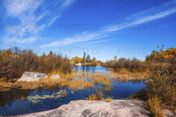 Old Pinawa Dam Provincial Heritage Park. Warm day. Yellow autumn grass is reflected in the Winnipeg