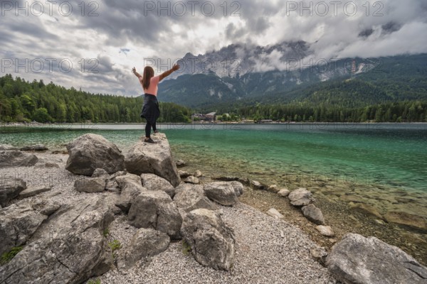 Zugspitze Peak top of Germany Alps mountain range and Eibsee Lake with woman tourist, Garmisch