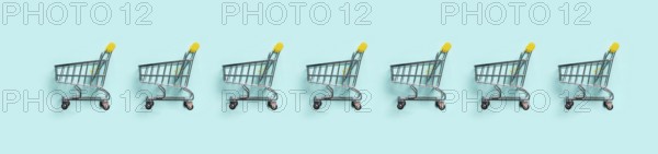 Shopping cart in row on blue background. Minimalism style. Toy trolley for supermarket. Top view or