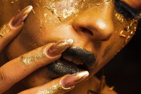 Beauty fashion model girl with golden make up and body on black background. Golden body art. The