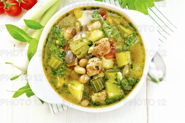Soup with pisto sauce, pork fat, tomatoes, zucchini, beans, celery and leek in a bowl on a napkin