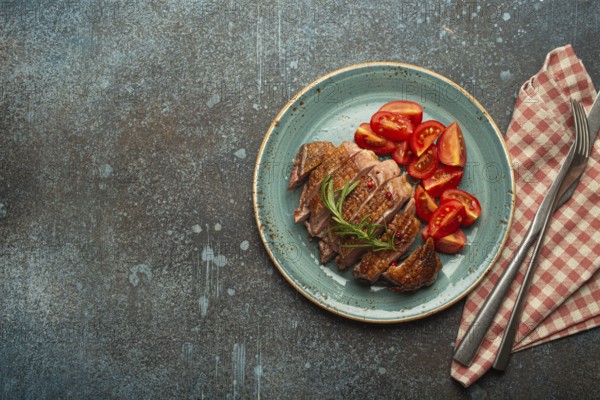 Delicious roasted sliced duck breast fillet with golden crispy skin, with pepper and rosemary, top
