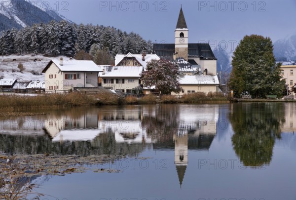 The church in the village Tarasp reflecting in the Taraspsee in the Swiss community Scuol in the