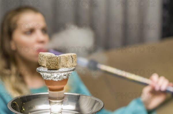 Woman in background blurred, smoking traditional Hookah (Narguile, Shisha, Chicha, Arguile),