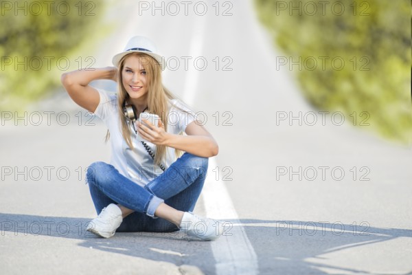 Happy young woman with vintage headphones around her neck, surfing the internet on her smartphone