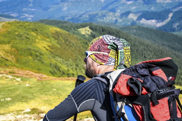 Man hiker on the trail hiking the mountain. A man sitting on a trail and looks at the beautiful