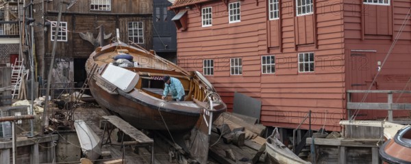 Spakenburg, The Netherlands - Fedbruary 19, 2021: Man inspecting historic ship at wooden ship wharf