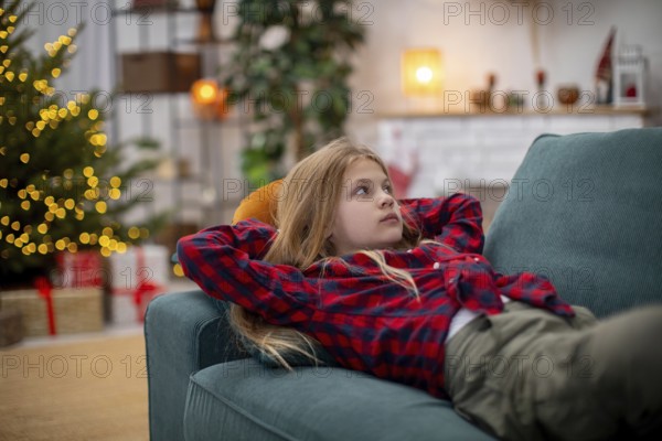 A young child lounges comfortably on a plush sofa, thoroughly enjoying the warm and cozy atmosphere