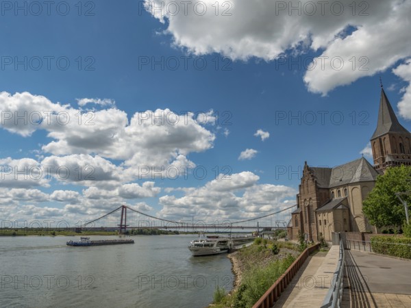 Historic church with a bridge and a ship on the river under a cloudy sky, emmerich, lower rhine,